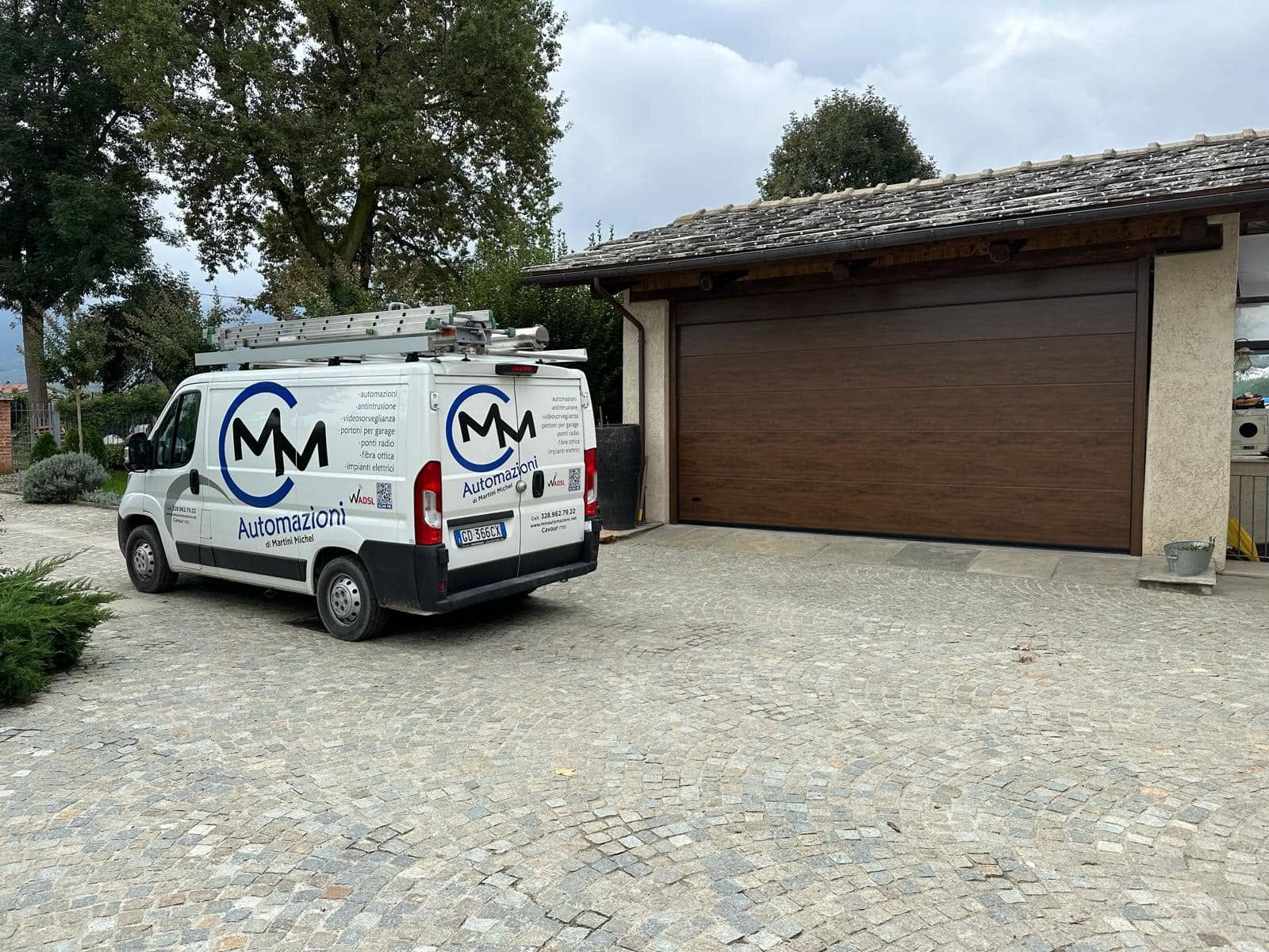 Chi siamo 2 Furgone di MM Automazioni davanti a un portone sezionale appena installato a Cavour